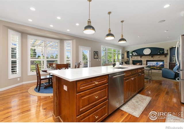 6582 Spanish Bay Dr, Windsor, CO 80550 - kitchen featuring appliances with stainless steel finishes, crown molding, wood finished floors, open floor plan, and a fireplace