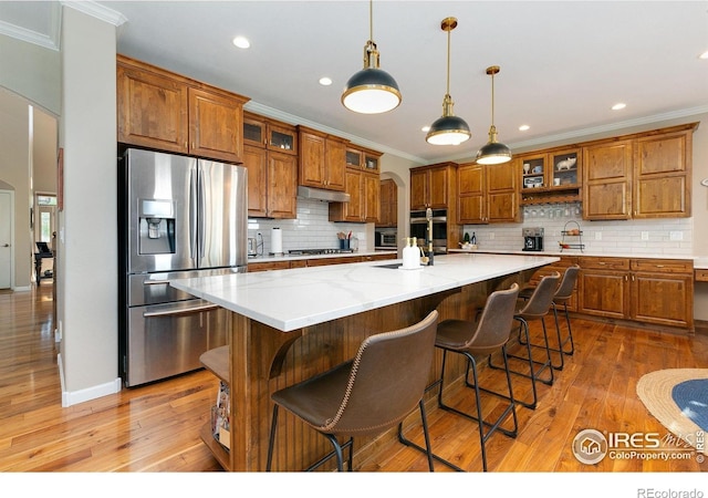 6582 Spanish Bay Dr, Windsor, CO 80550 - kitchen with appliances with stainless steel finishes, brown cabinetry, light wood-style floors, ornamental molding, and recessed lighting