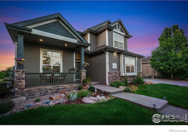 6582 Spanish Bay Dr, Windsor, CO 80550 - view of front of home featuring covered porch, stone siding, and a lawn
