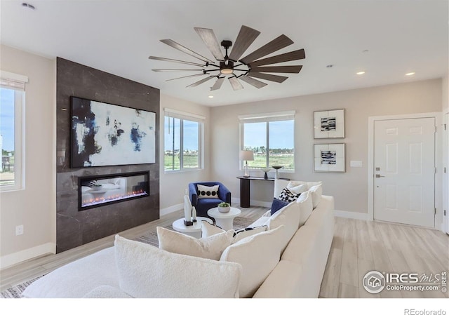 2770 Bear Springs Cir, Longmont, CO 80503 - living room featuring a tiled fireplace, light wood-style floors, recessed lighting, and a ceiling fan