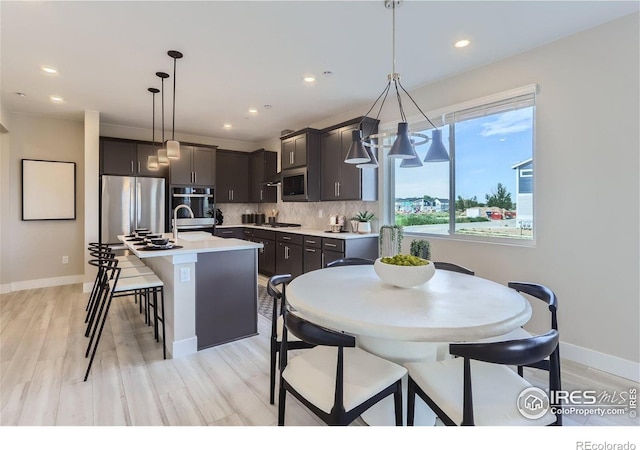 2770 Bear Springs Cir, Longmont, CO 80503 - kitchen with stainless steel appliances, light countertops, an island with sink, tasteful backsplash, and light wood-style floors