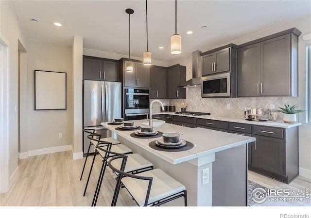 2770 Bear Springs Cir, Longmont, CO 80503 - kitchen featuring appliances with stainless steel finishes, wall chimney range hood, decorative backsplash, light countertops, and an island with sink