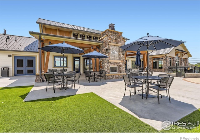 2770 Bear Springs Cir, Longmont, CO 80503 - back of property with a standing seam roof, stone siding, a metal roof, an outdoor stone fireplace, and a patio area