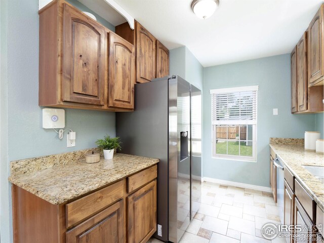 1750 Trenton St, Denver, CO 80220 - kitchen with stainless steel appliances, brown cabinets, and light stone countertops