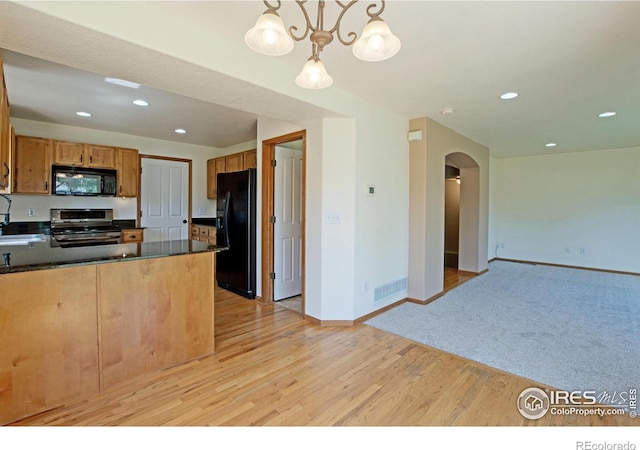 3268 White Buffalo Dr, Wellington, CO 80549 - kitchen featuring black appliances, arched walkways, dark countertops, light wood-style flooring, and recessed lighting
