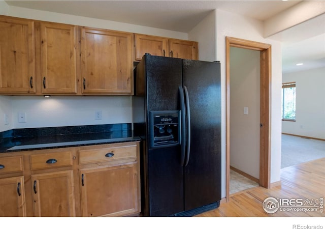3268 White Buffalo Dr, Wellington, CO 80549 - kitchen featuring black fridge, dark stone counters, light wood-type flooring, and brown cabinets