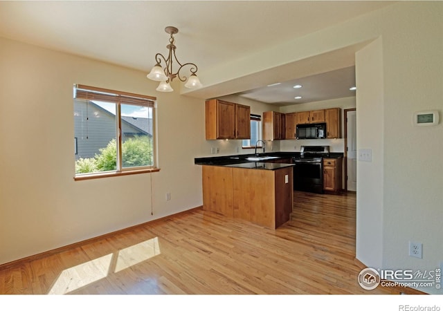 3268 White Buffalo Dr, Wellington, CO 80549 - kitchen with stainless steel range with gas cooktop, black microwave, a peninsula, dark countertops, and light wood-type flooring