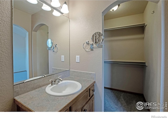 3268 White Buffalo Dr, Wellington, CO 80549 - bathroom featuring vanity, a textured wall, and a spacious closet