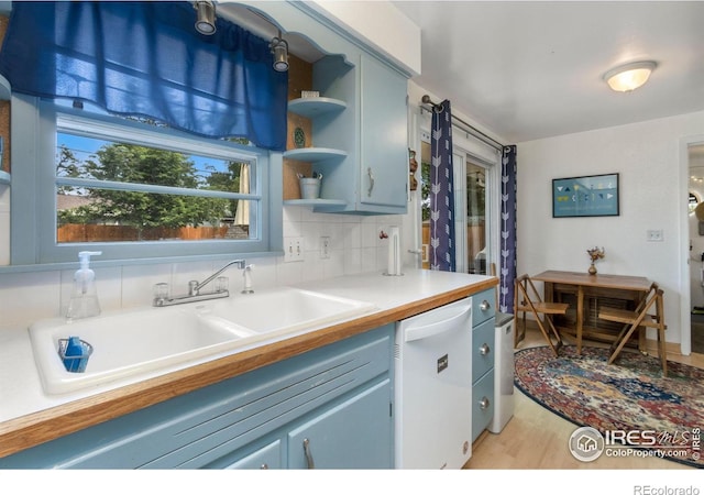 408 Riddle Dr, Fort Collins, CO 80521 - kitchen featuring dishwasher, open shelves, light wood-type flooring, light countertops, and backsplash