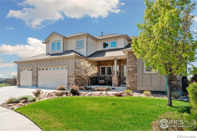 5954 Black Lion Ct, Windsor, CO 80550 - view of front of property featuring board and batten siding, a front lawn, concrete driveway, a porch, and stone siding