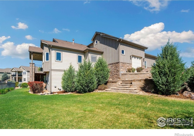 5954 Black Lion Ct, Windsor, CO 80550 - back of house featuring a garage, board and batten siding, a yard, and stone siding