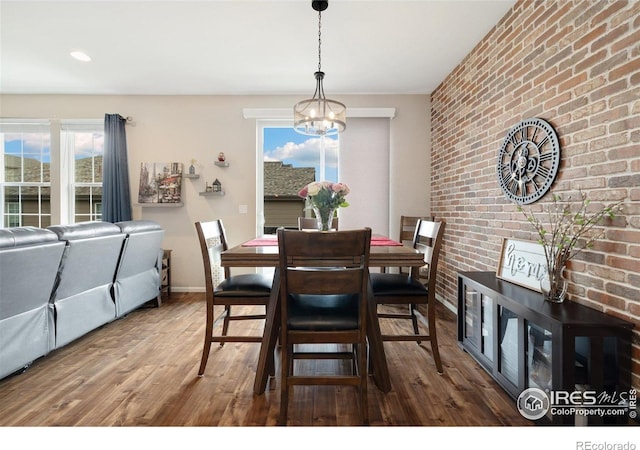 4822 Wildflower Pl, Dacono, CO 80514 - dining space featuring wood finished floors, brick wall, and a chandelier