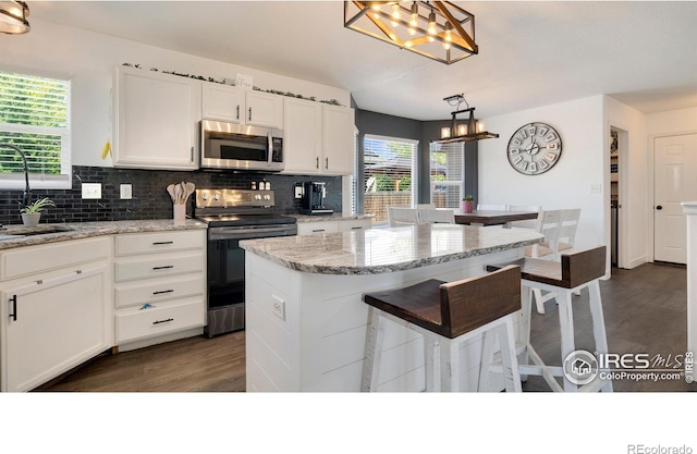 3007 45th Ave, Greeley, CO 80634 - kitchen featuring appliances with stainless steel finishes, a chandelier, decorative backsplash, and white cabinets