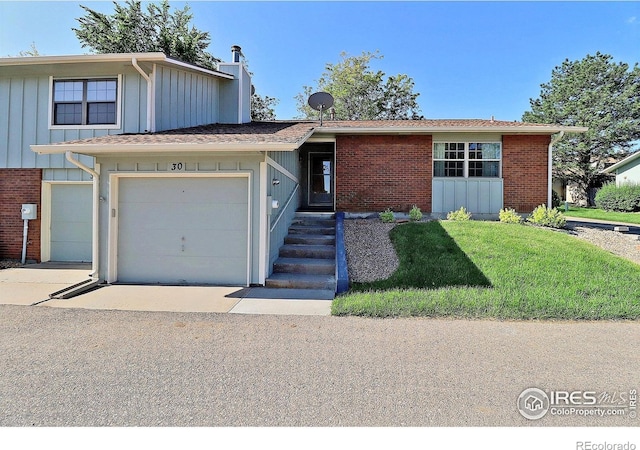 3405 W 16th St Unit 30, Greeley, CO 80634 - view of front of property with board and batten siding, driveway, brick siding, an attached garage, and a front yard