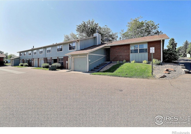 3405 W 16th St Unit 30, Greeley, CO 80634 - view of front of home with brick siding, a garage, a chimney, and a front yard
