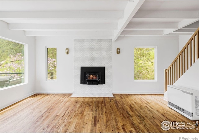 781 Cold Springs Rd, Nederland, CO 80466 - unfurnished living room featuring beam ceiling, wood finished floors, a fireplace, and stairs