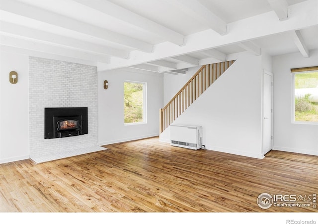 781 Cold Springs Rd, Nederland, CO 80466 - unfurnished living room featuring wood finished floors, stairway, heating unit, beam ceiling, and a tile fireplace