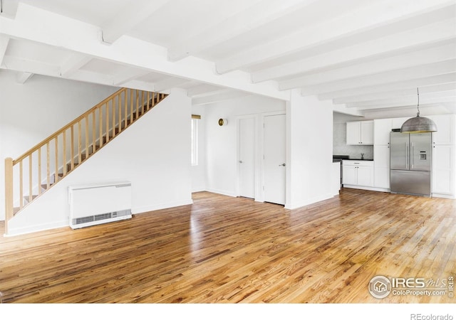 781 Cold Springs Rd, Nederland, CO 80466 - unfurnished living room with light wood-style flooring, beamed ceiling, heating unit, and stairway