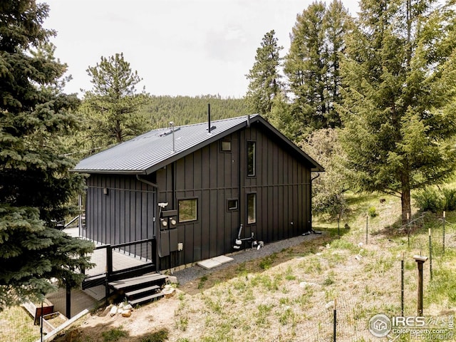 781 Cold Springs Rd, Nederland, CO 80466 - rear view of property with board and batten siding, a wooden deck, a metal roof, and a forest view