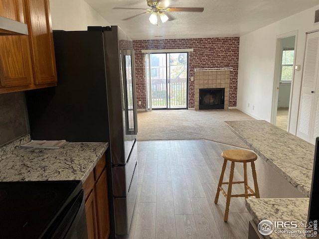 225 E 8th Ave Unit B11, Longmont, CO 80504 - kitchen with ceiling fan, exhaust hood, brown cabinetry, freestanding refrigerator, and light wood-style floors
