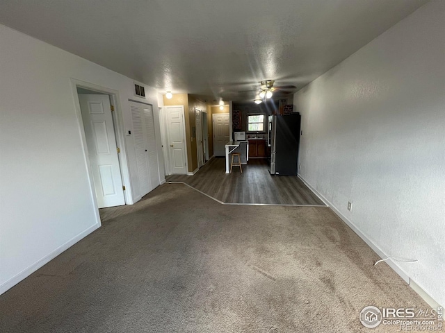 225 E 8th Ave Unit B11, Longmont, CO 80504 - unfurnished living room featuring a ceiling fan and dark colored carpet
