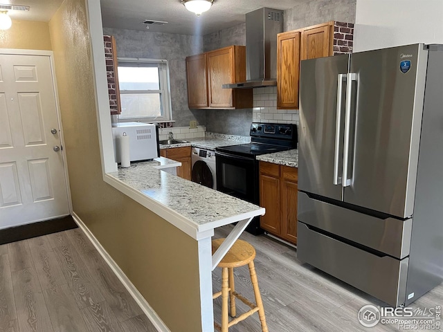 225 E 8th Ave Unit B11, Longmont, CO 80504 - kitchen with freestanding refrigerator, wall chimney exhaust hood, electric range, washer / clothes dryer, and light wood finished floors