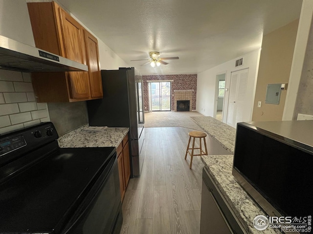 225 E 8th Ave Unit B11, Longmont, CO 80504 - kitchen with black electric range, wall chimney exhaust hood, a ceiling fan, stainless steel microwave, and brown cabinets