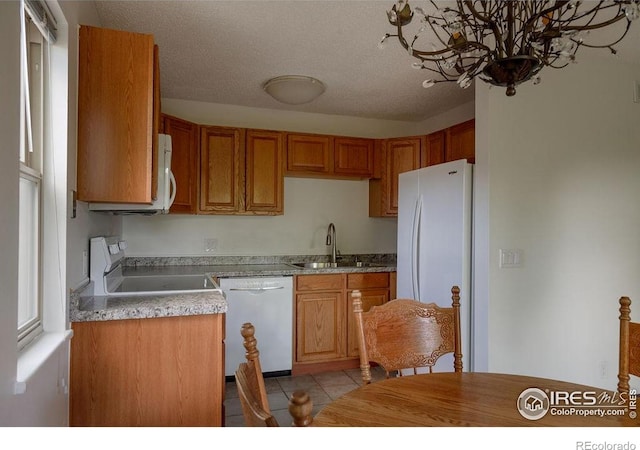 3345 Chisholm Trl Unit 206, Boulder, CO 80301 - kitchen featuring white appliances, light tile patterned flooring, light countertops, brown cabinetry, and a chandelier