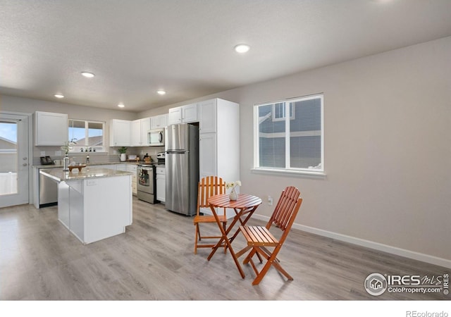 4216 Yellowbells Dr, Evans, CO 80620 - kitchen with appliances with stainless steel finishes, light wood-type flooring, a kitchen island, recessed lighting, and white cabinets