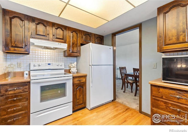 610 S Broadway Ave, Fort Lupton, CO 80621 - kitchen with white appliances, under cabinet range hood, light wood finished floors, and light countertops