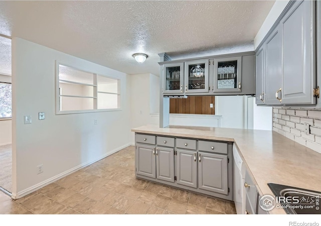 131 E 15th Ave, Longmont, CO 80504 - kitchen featuring gray cabinets, a peninsula, plenty of natural light, a textured ceiling, and light countertops