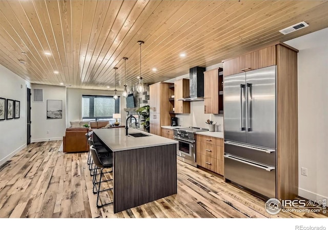 1109 Neon Forest Cir # 2, Longmont, CO 80504 - kitchen featuring premium appliances, wall chimney exhaust hood, wooden ceiling, light wood-style flooring, and a kitchen breakfast bar