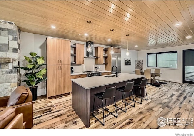 1109 Neon Forest Cir # 2, Longmont, CO 80504 - kitchen featuring wall chimney range hood, a kitchen breakfast bar, a kitchen island with sink, wooden ceiling, and light wood-type flooring