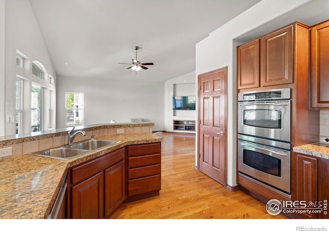 1513 Cannon Mountain Dr, Longmont, CO 80503 - kitchen featuring stainless steel appliances, light wood finished floors, a ceiling fan, brown cabinetry, and open floor plan