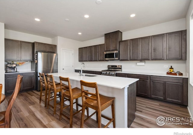 3775 Ginkgo St, Wellington, CO 80549 - kitchen featuring stainless steel appliances, wood finished floors, dark brown cabinetry, recessed lighting, and a breakfast bar area