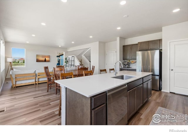 3775 Ginkgo St, Wellington, CO 80549 - kitchen featuring appliances with stainless steel finishes, light wood-style floors, light countertops, a center island with sink, and recessed lighting