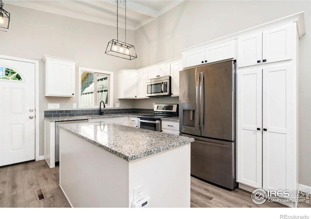 3012 Anchor Way Unit 3, Fort Collins, CO 80525 - kitchen with appliances with stainless steel finishes, a high ceiling, light wood-style floors, a center island, and white cabinets