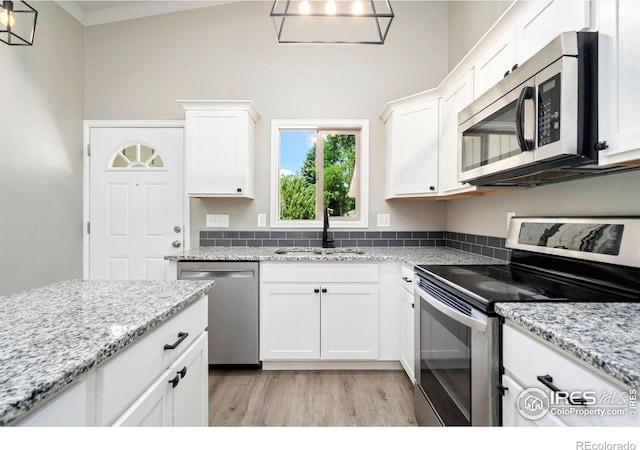 3012 Anchor Way Unit 3, Fort Collins, CO 80525 - kitchen featuring appliances with stainless steel finishes, light wood finished floors, white cabinets, and light stone counters
