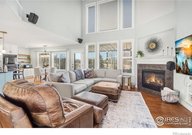 8356 Louden Circle Ft, Collins, CO 80528 - living area featuring a towering ceiling, a fireplace, wood finished floors, and a chandelier