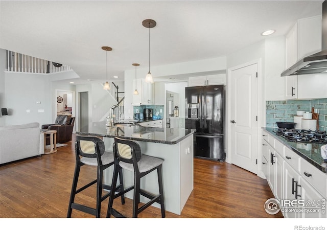 8356 Louden Circle Ft, Collins, CO 80528 - kitchen featuring black appliances, wall chimney range hood, tasteful backsplash, open floor plan, and a breakfast bar