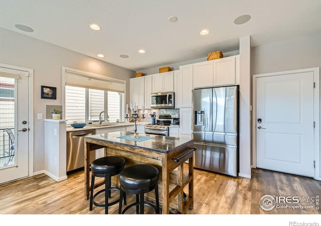1419 W 67th Ave, Denver, CO 80221 - kitchen with stainless steel appliances, light wood finished floors, plenty of natural light, white cabinets, and recessed lighting