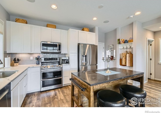 1419 W 67th Ave, Denver, CO 80221 - kitchen featuring stainless steel appliances, light wood finished floors, white cabinetry, tasteful backsplash, and recessed lighting