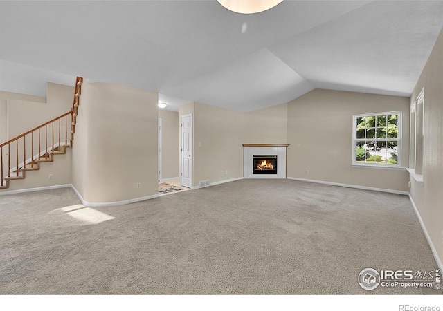 3132 Concord Way, Longmont, CO 80503 - unfurnished living room featuring carpet floors, stairway, vaulted ceiling, and a lit fireplace