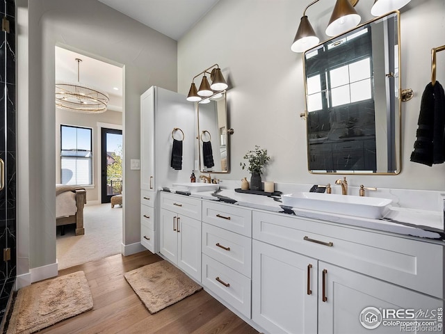 1255 Eliza Ave, Berthoud, CO 80513 - bathroom with wood finished floors, double vanity, ensuite bathroom, and a chandelier