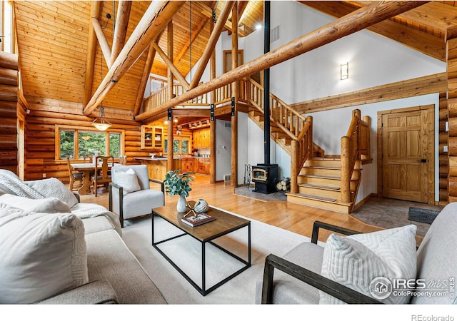 178 Hazelwood Dr, Nederland, CO 80466 - living area featuring log walls, high vaulted ceiling, stairway, wood finished floors, and a wood stove
