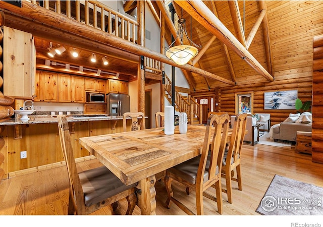 178 Hazelwood Dr, Nederland, CO 80466 - dining room with high vaulted ceiling, log walls, a wood ceiling with exposed beams, light wood finished floors, and stairway