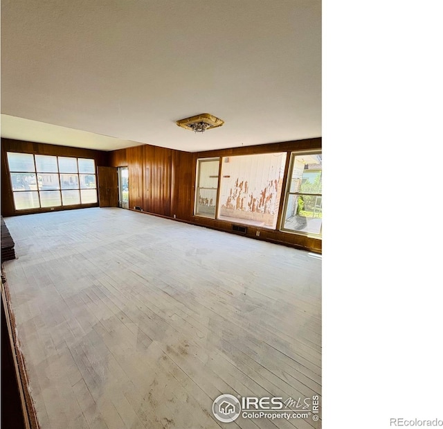 151 W 1st St N, Cheyenne Wells, CO 80810 - empty room featuring wooden walls, plenty of natural light, and wood finished floors