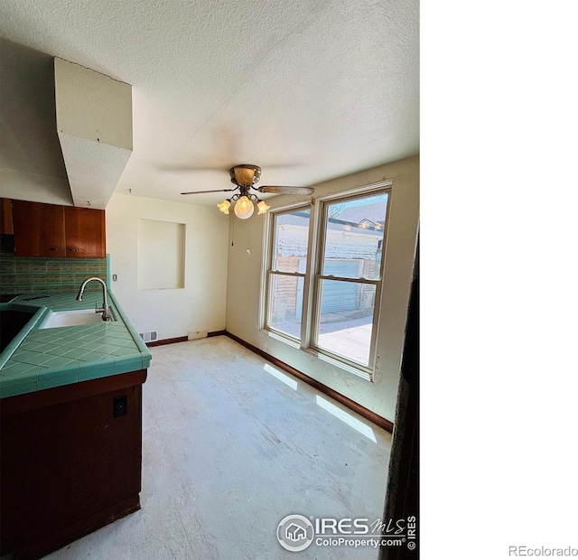 151 W 1st St N, Cheyenne Wells, CO 80810 - kitchen featuring decorative backsplash, tile countertops, a ceiling fan, light carpet, and a textured ceiling
