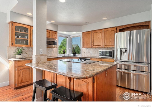 4615 Kitchell Way, Fort Collins, CO 80524 - kitchen featuring stainless steel appliances, light wood-style floors, a kitchen island, light stone countertops, and recessed lighting