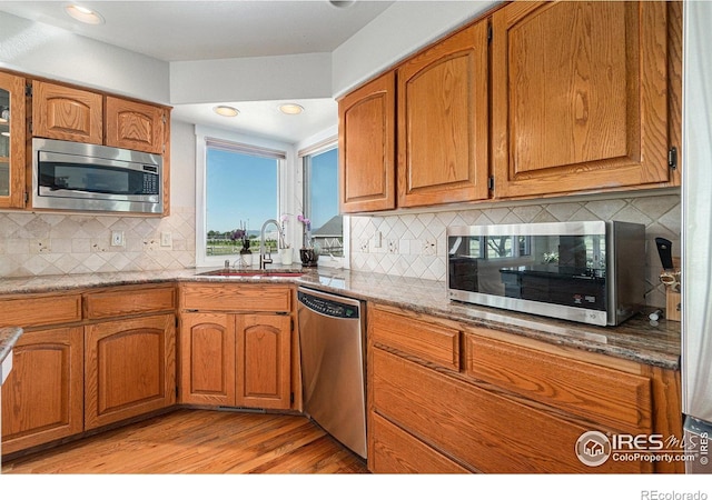 4615 Kitchell Way, Fort Collins, CO 80524 - kitchen with stainless steel appliances, light wood-style flooring, tasteful backsplash, brown cabinetry, and recessed lighting